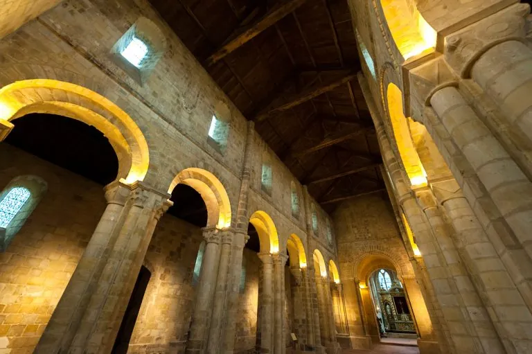 Nef romane de l'Abbaye de Graville, arcades de pierre éclairées en doré